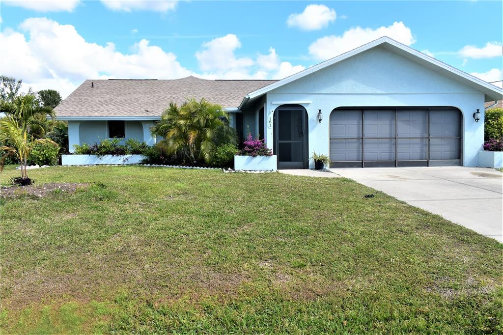 A light blue single-story house features a front-facing garage, a screened entryway, and landscaping — 181 BUNKER ROAD, ROTONDA WEST, FL