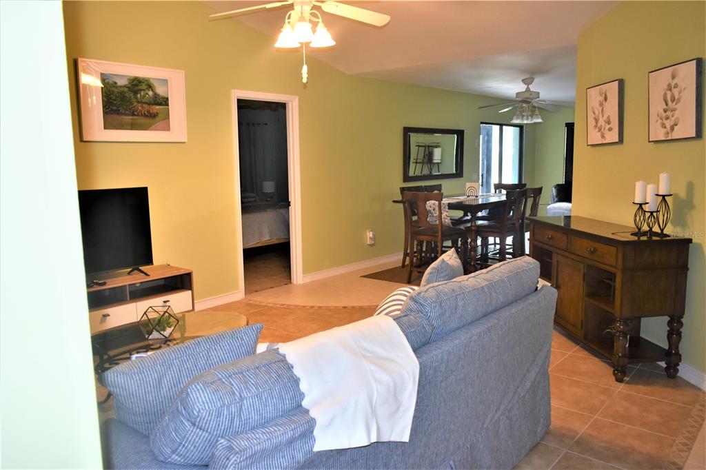 A living room with a blue sofa, television, dining area, and light green walls — 181 BUNKER ROAD, ROTONDA WEST, FL
