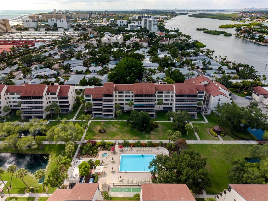 An aerial view shows a multi-story apartment building with a swimming pool and landscaped grounds — 6267 MIDNIGHT PASS ROAD UNIT 306, SARASOTA, FL