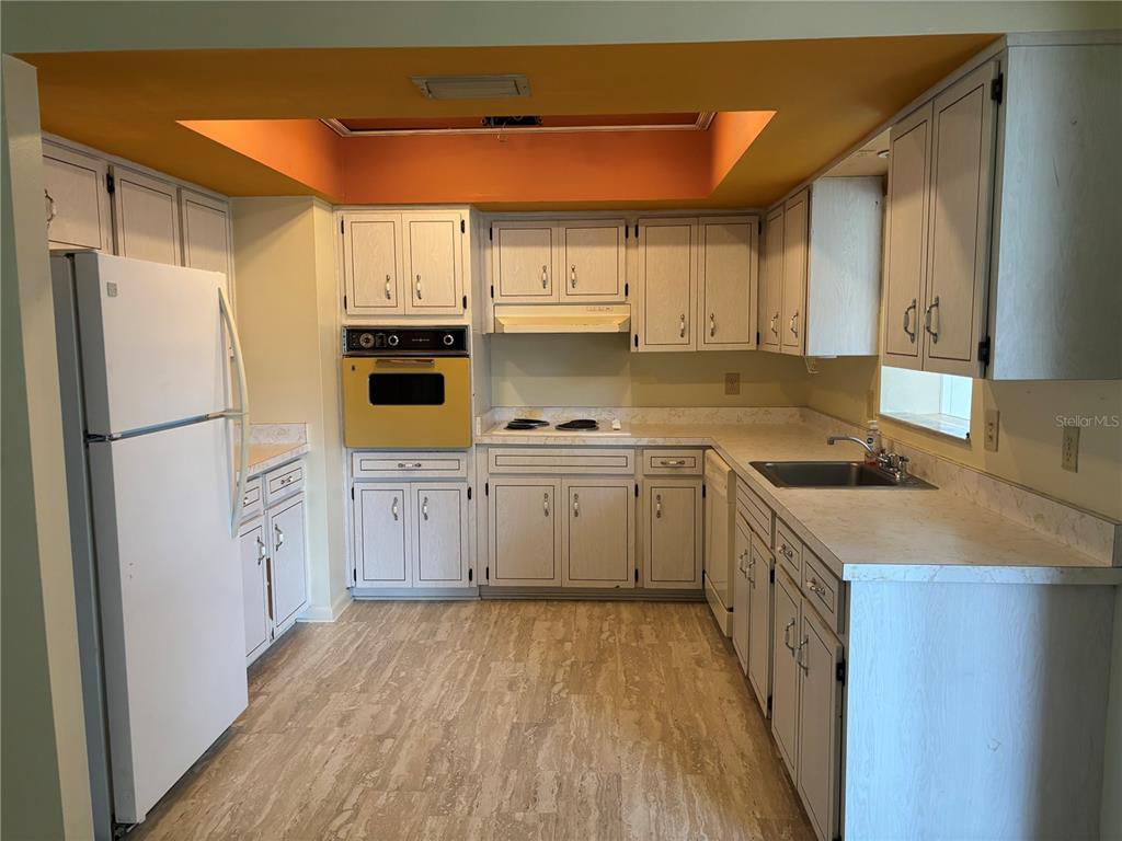 A kitchen features white cabinets, a yellow wall oven, and light-colored laminate countertops — 808 SPRUCE STREET, INVERNESS, FL