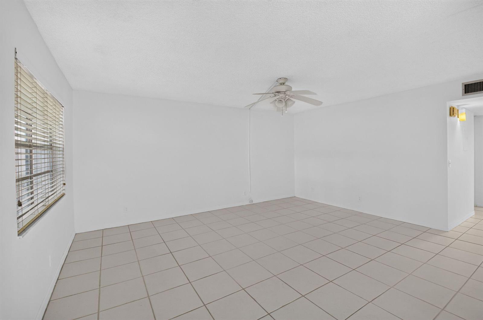 An empty room with white walls, light-colored tile flooring, and a ceiling fan — 200 Normandy E # 200, Delray Beach FL 33484, DELRAY BEACH, FL