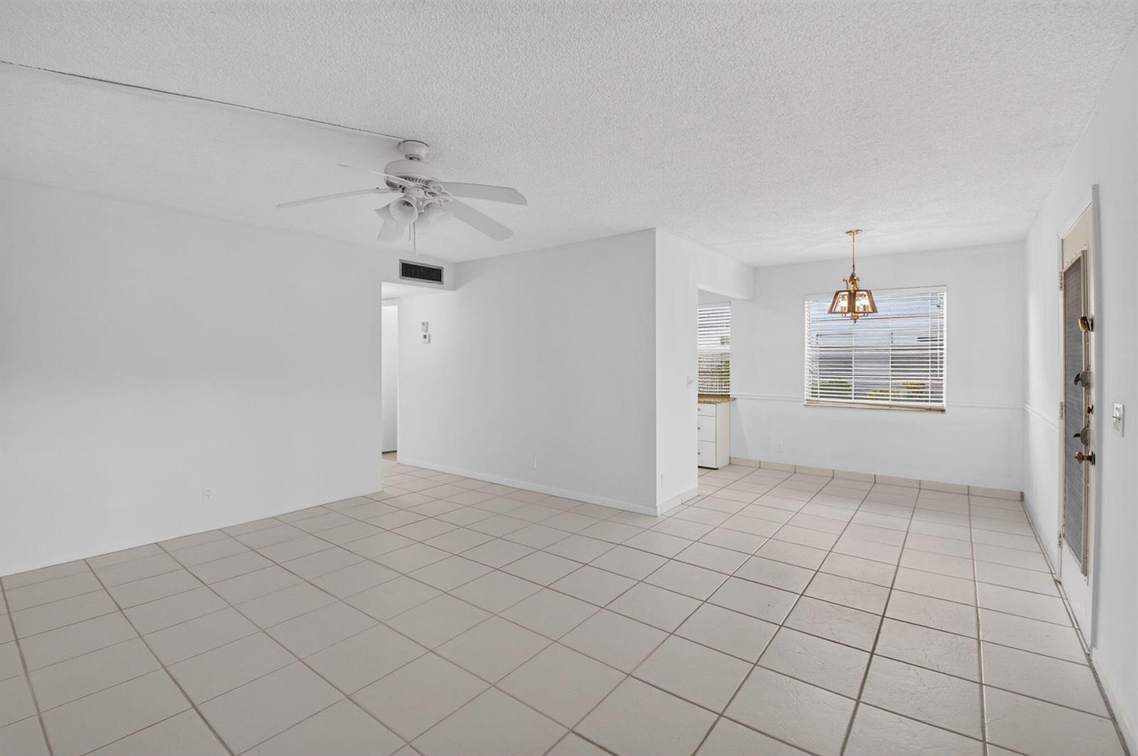 An empty room with white walls, light-colored tile flooring, a ceiling fan, and a window — 200 Normandy E # 200, Delray Beach FL 33484, DELRAY BEACH, FL