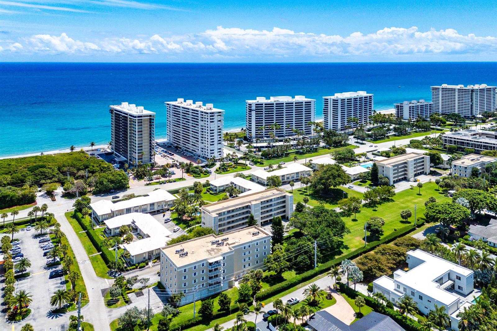An aerial view shows several multi-story residential buildings situated near a beach and ocean — 1299 S Ocean Boulevard # R12, Boca Raton FL 33432, BOCA RATON, FL