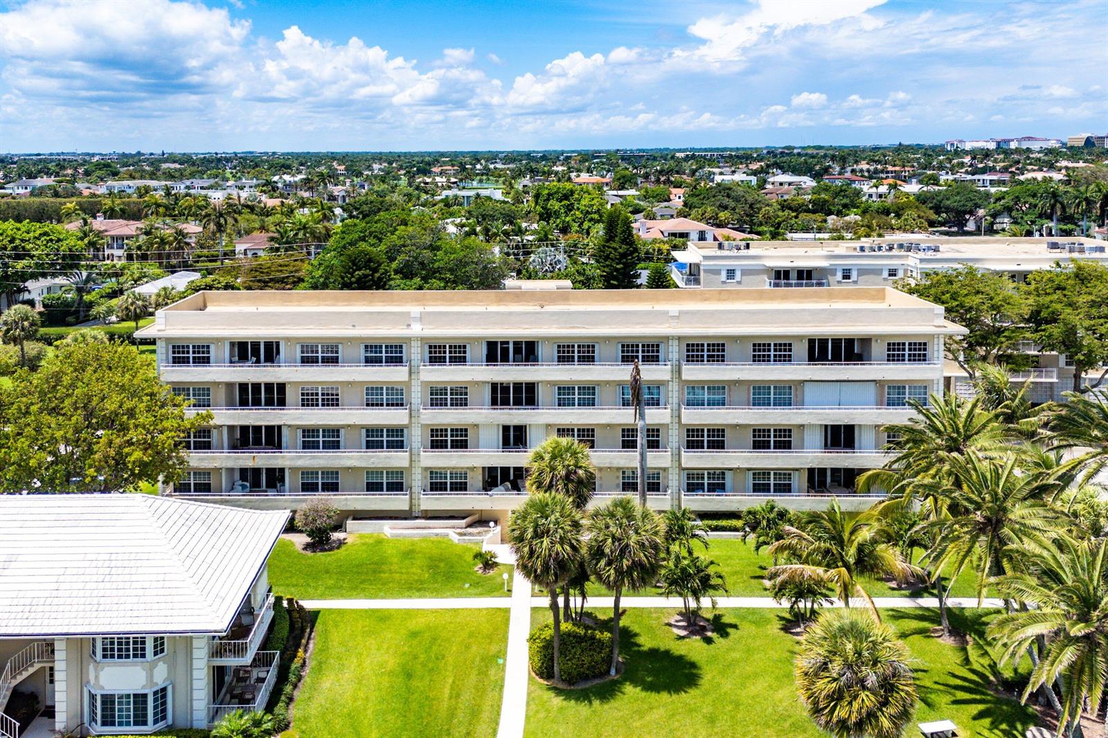 An aerial view shows a multi-story apartment building surrounded by palm trees and green lawns — 1299 S Ocean Boulevard # R12, Boca Raton FL 33432, BOCA RATON, FL