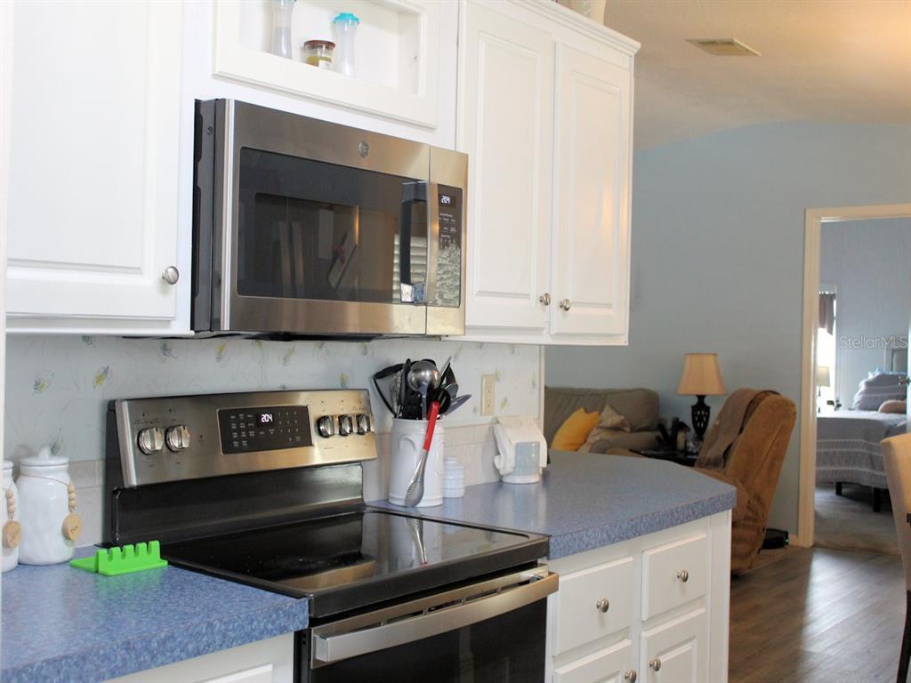 A kitchen features white cabinets, stainless steel appliances, and blue countertops — 64 THATCH PALM STREET W, LARGO, FL
