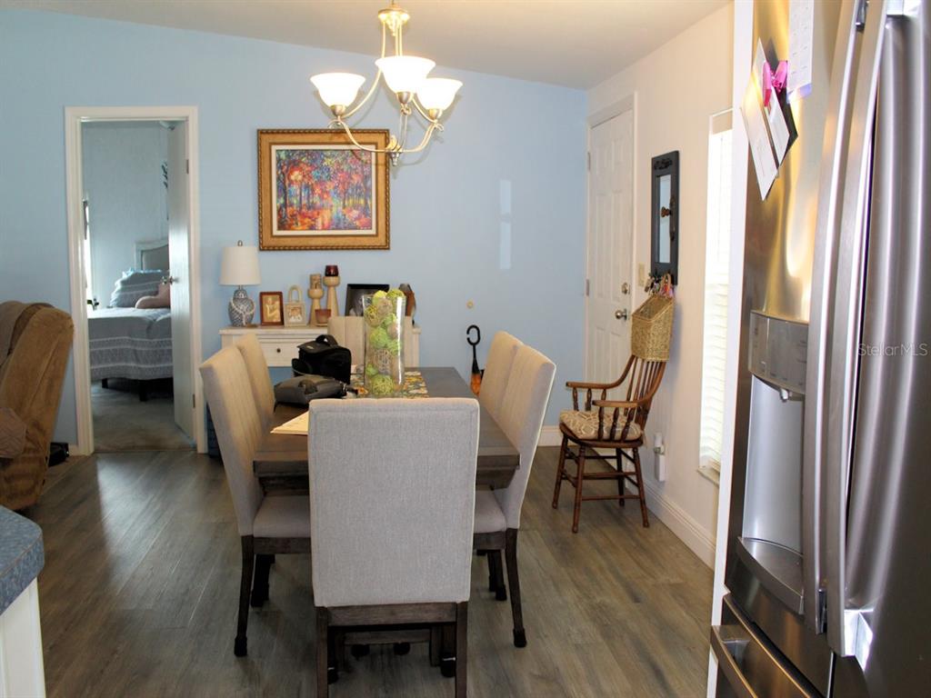 A dining room features a wooden table with upholstered chairs, a chandelier, and light-blue walls — 64 THATCH PALM STREET W, LARGO, FL