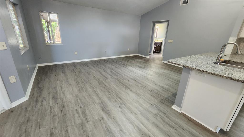 An open-concept living area features gray walls, wood-look flooring, and a kitchen with granite countertops — 300 SUN OAKS COURT, LAKE MARY, FL