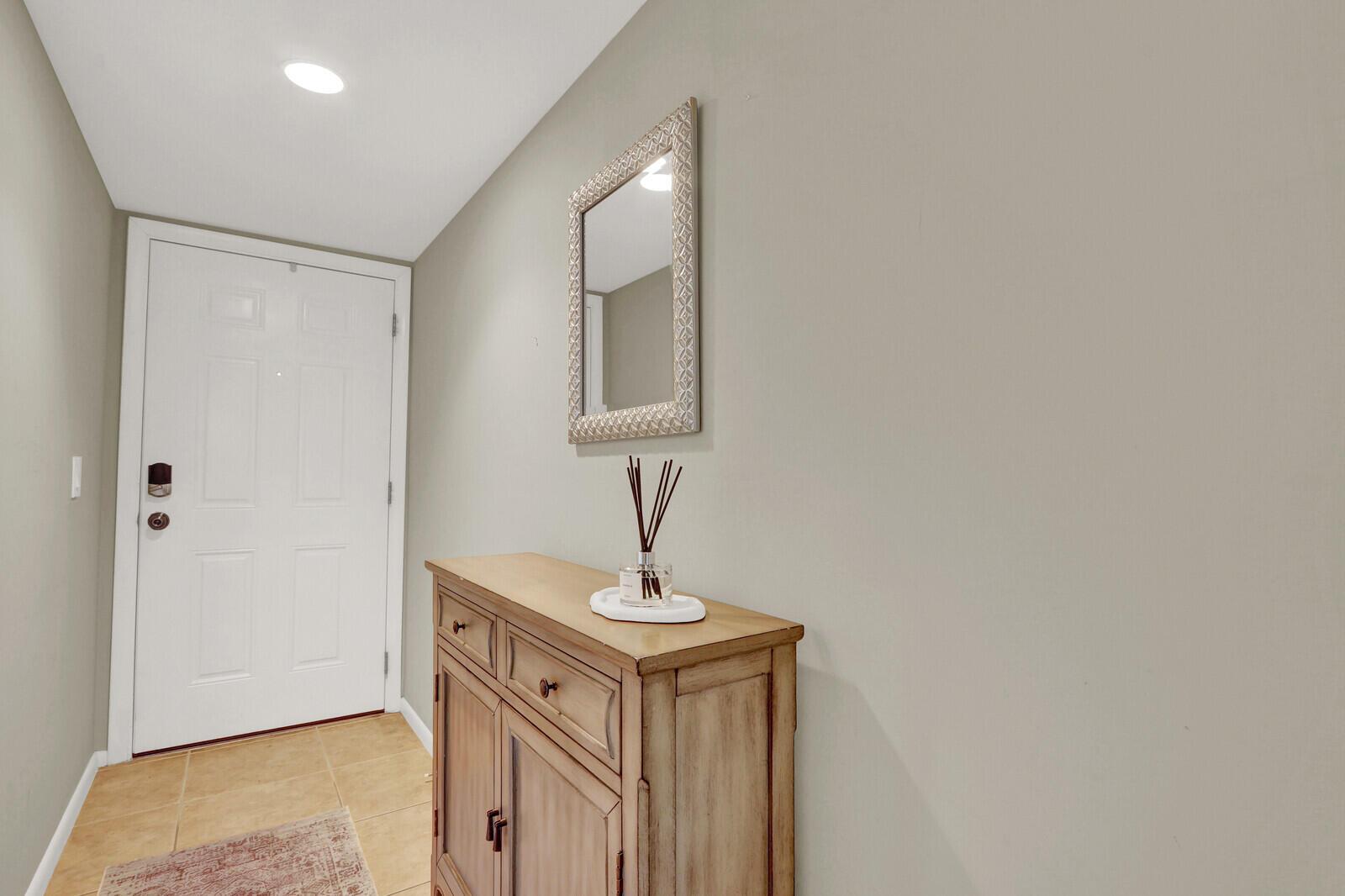 An entryway features a white door, a wooden cabinet, and a wall-mounted mirror — 901 Seafarer Circle # 403, Jupiter FL 33477, JUPITER, FL