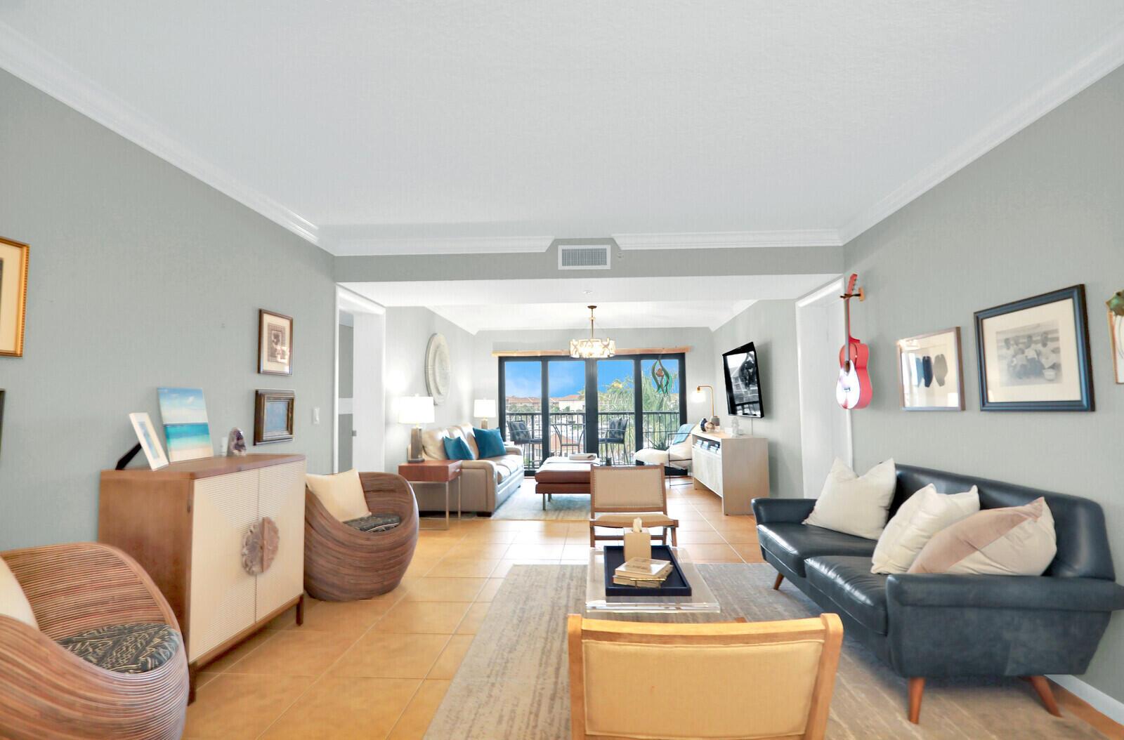 A living room features light gray walls, tile flooring, a dark sofa, and balcony access — 901 Seafarer Circle # 403, Jupiter FL 33477, JUPITER, FL