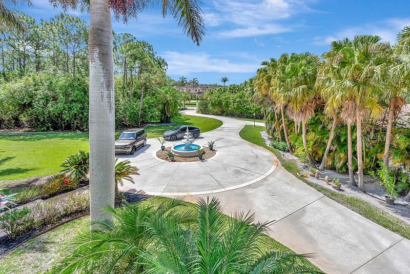 A circular driveway with a central fountain leads to a house surrounded by palm trees — 2584 SE RANCH ACRES CIRCLE, JUPITER, FL