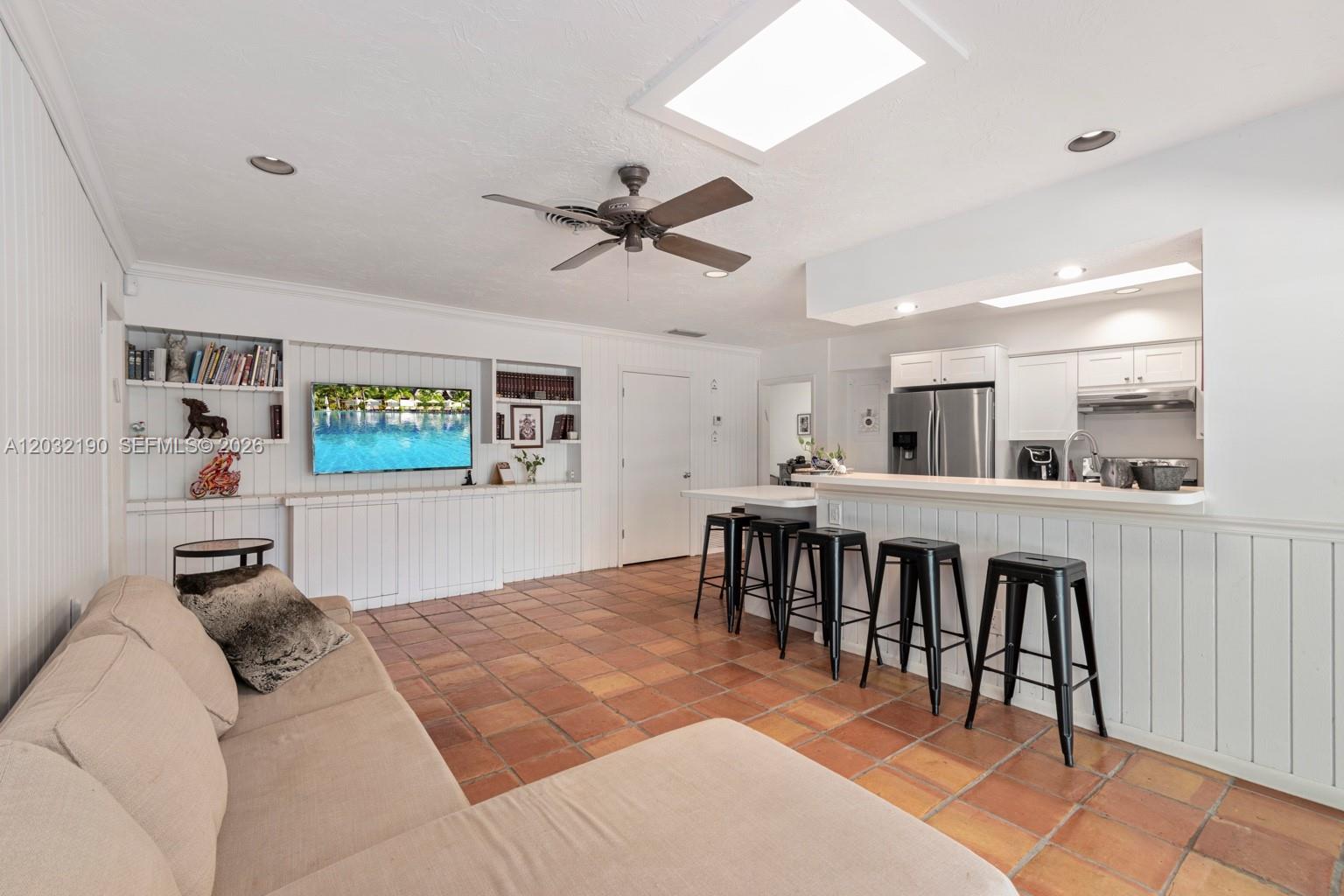 A living room with terracotta tile floors, a sectional sofa, and an open kitchen — 19950 NE 24th Ave # 1, Miami FL 33180, MIAMI, FL