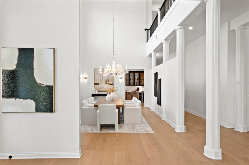 A dining area with a chandelier and table sits beneath a high ceiling with columns — 6324 W MACLAURIN DRIVE, TAMPA, FL
