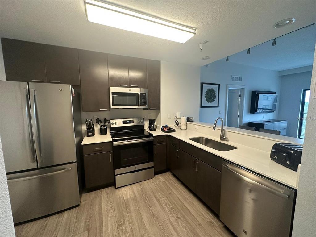 A kitchen features dark wood cabinets, stainless steel appliances, and white countertops — 14501 GROVE RESORT AVENUE UNIT 3406, WINTER GARDEN, FL