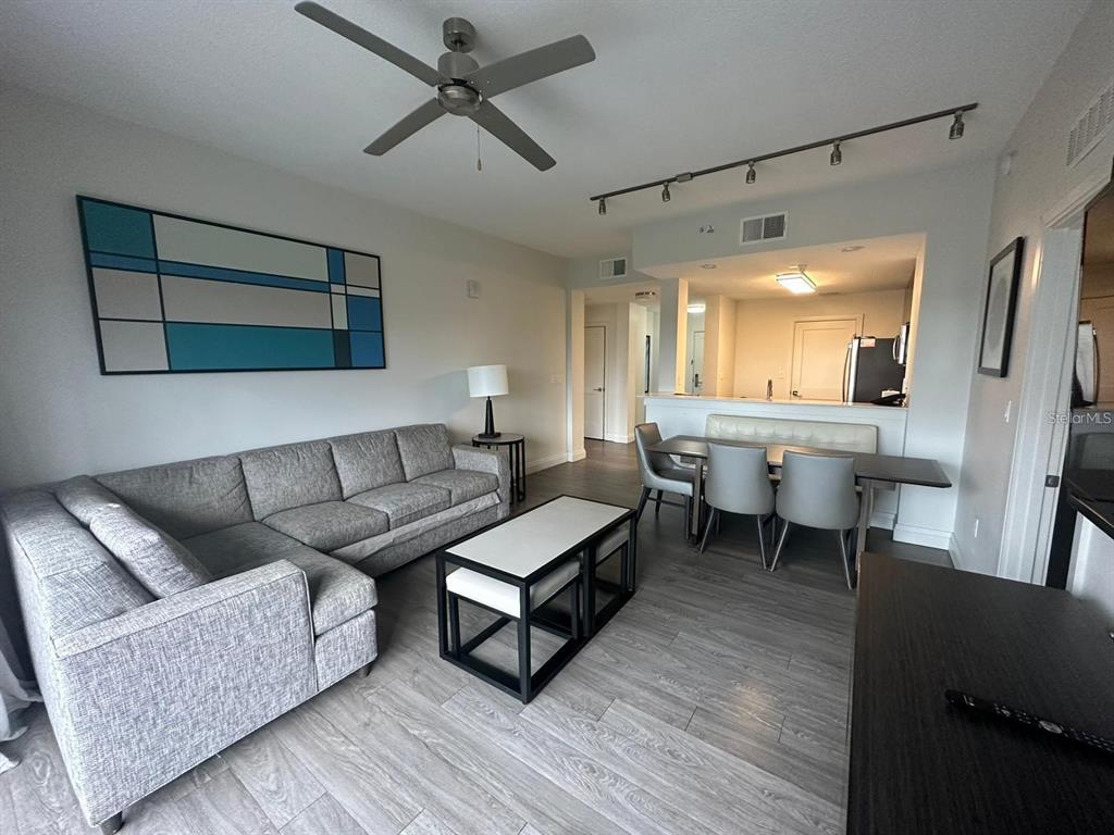 A living and dining area features a gray sectional sofa, dining table, and wood flooring — 14501 GROVE RESORT AVENUE UNIT 3406, WINTER GARDEN, FL