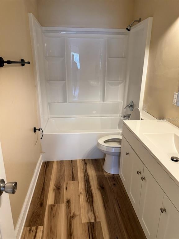 A bathroom features a white tub-shower combo, a toilet, and a white vanity cabinet — 128 11TH WAHNETA STREET W, WINTER HAVEN, FL