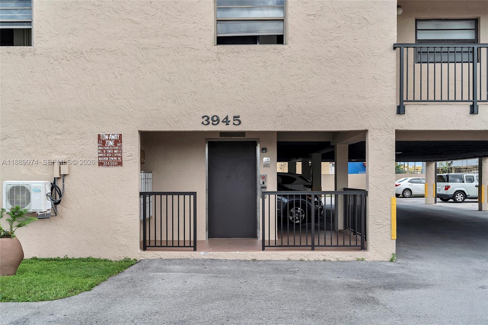 The exterior of a beige building features a ground-level entrance, parking area, and metal railings — 3945 SW 89th Ave # 201, Miami FL 33165, MIAMI, FL