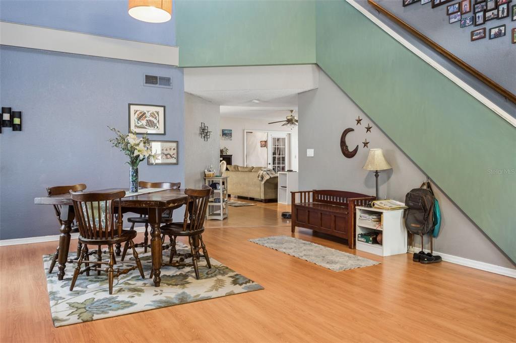 A dining area with a wooden table and chairs sits beside a staircase and entryway — 3237 MONTROSE CIRCLE, PALM HARBOR, FL