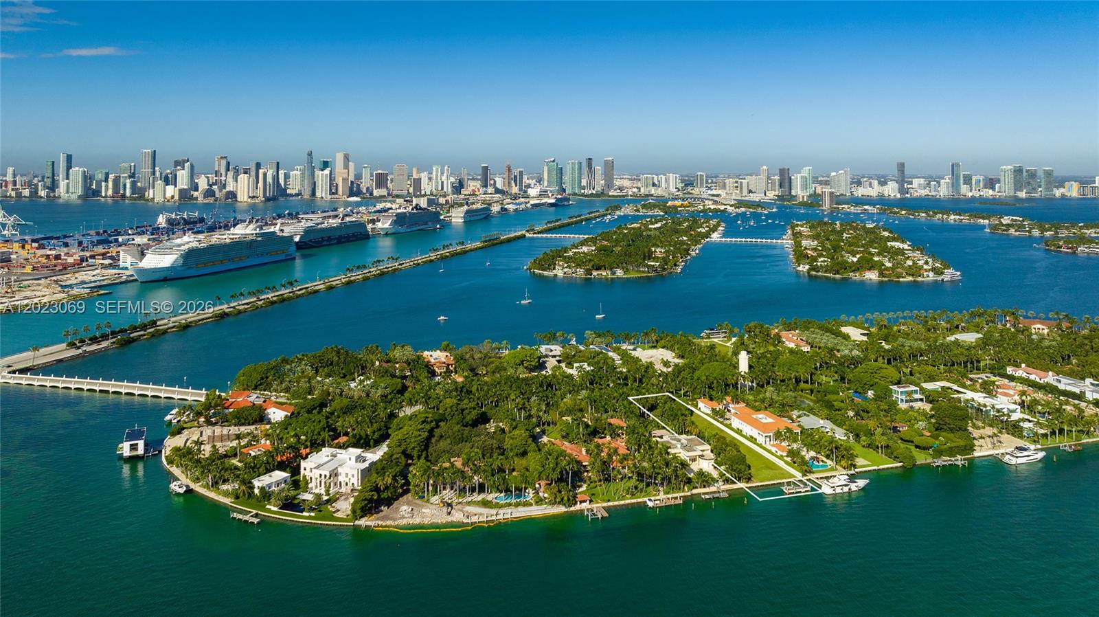 An aerial view shows a waterfront mansion on a lush island near a city skyline — 36 Star Island Dr, Miami Beach FL 33139, MIAMI BEACH, FL
