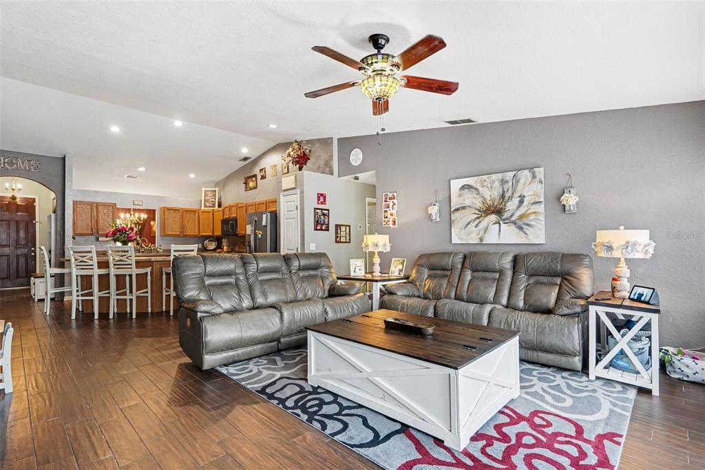 A living room with gray sofas, a white coffee table, and an open-concept kitchen — 423 MAJESTIC GARDENS BLVD, WINTER HAVEN, FL