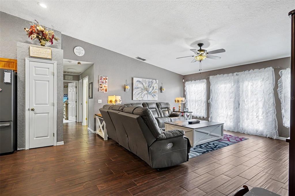 A living room features gray walls, dark wood-look tile flooring, a gray sectional, and sliding doors — 423 MAJESTIC GARDENS BLVD, WINTER HAVEN, FL