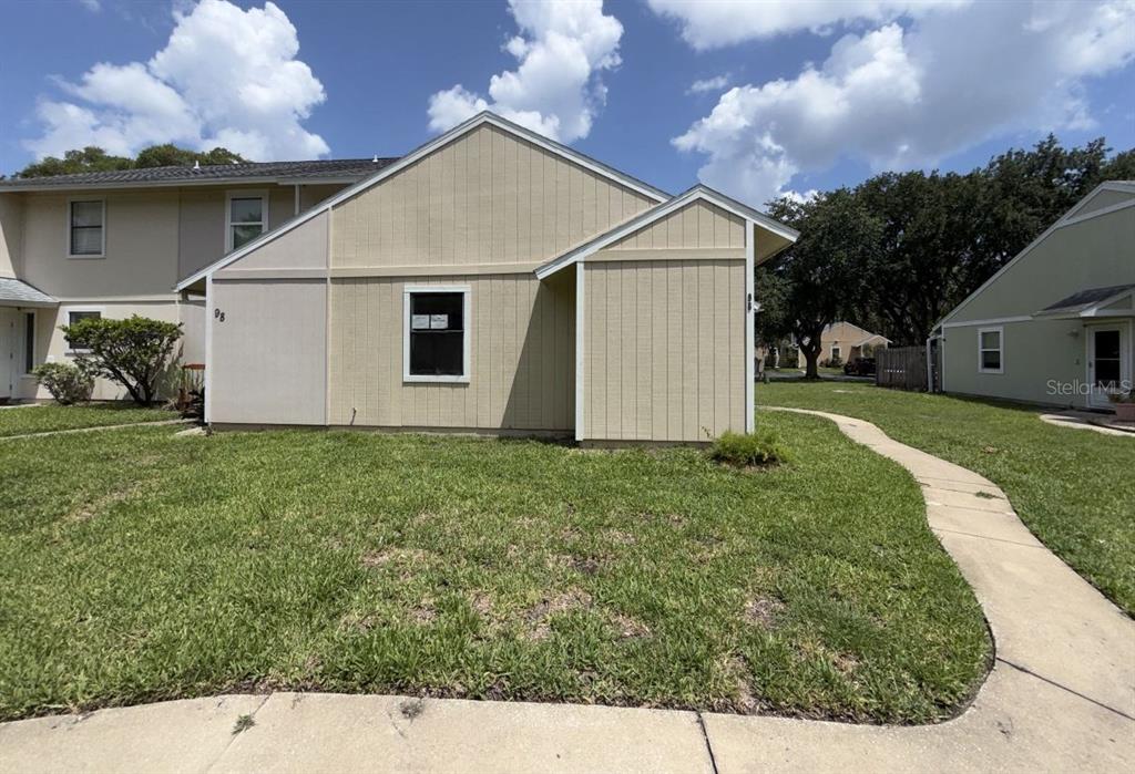 A beige, single-story residential building with vertical siding and a sidewalk in the foreground — 96 TOMOKA MEADOWS BOULEVARD, ORMOND BEACH, FL