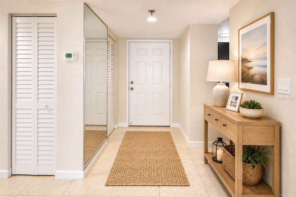 An entryway features a white door, a console table, a mirror, and a woven rug — 4550 PINEBROOK CIRCLE UNIT 106, BRADENTON, FL