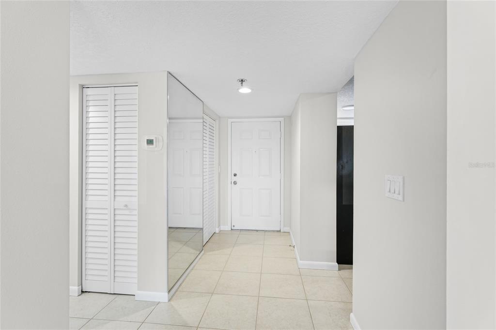 A bright entryway features white walls, tiled flooring, a mirrored closet, and a white front door — 4550 PINEBROOK CIRCLE UNIT 106, BRADENTON, FL