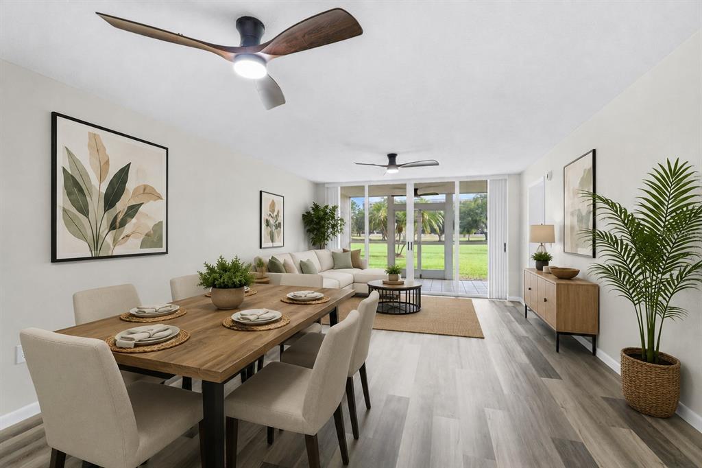A dining area and living room with wood-look flooring, ceiling fans, and a sliding glass door — 4550 PINEBROOK CIRCLE UNIT 106, BRADENTON, FL