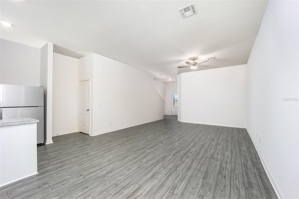 An open-concept living area features gray wood-look flooring, white walls, and a ceiling fan — 672 POPPY LANE, DUNDEE, FL