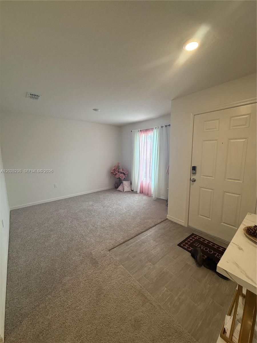 An entryway with tile flooring leads into a carpeted living area with a window — PORT ST. LUCIE, FL