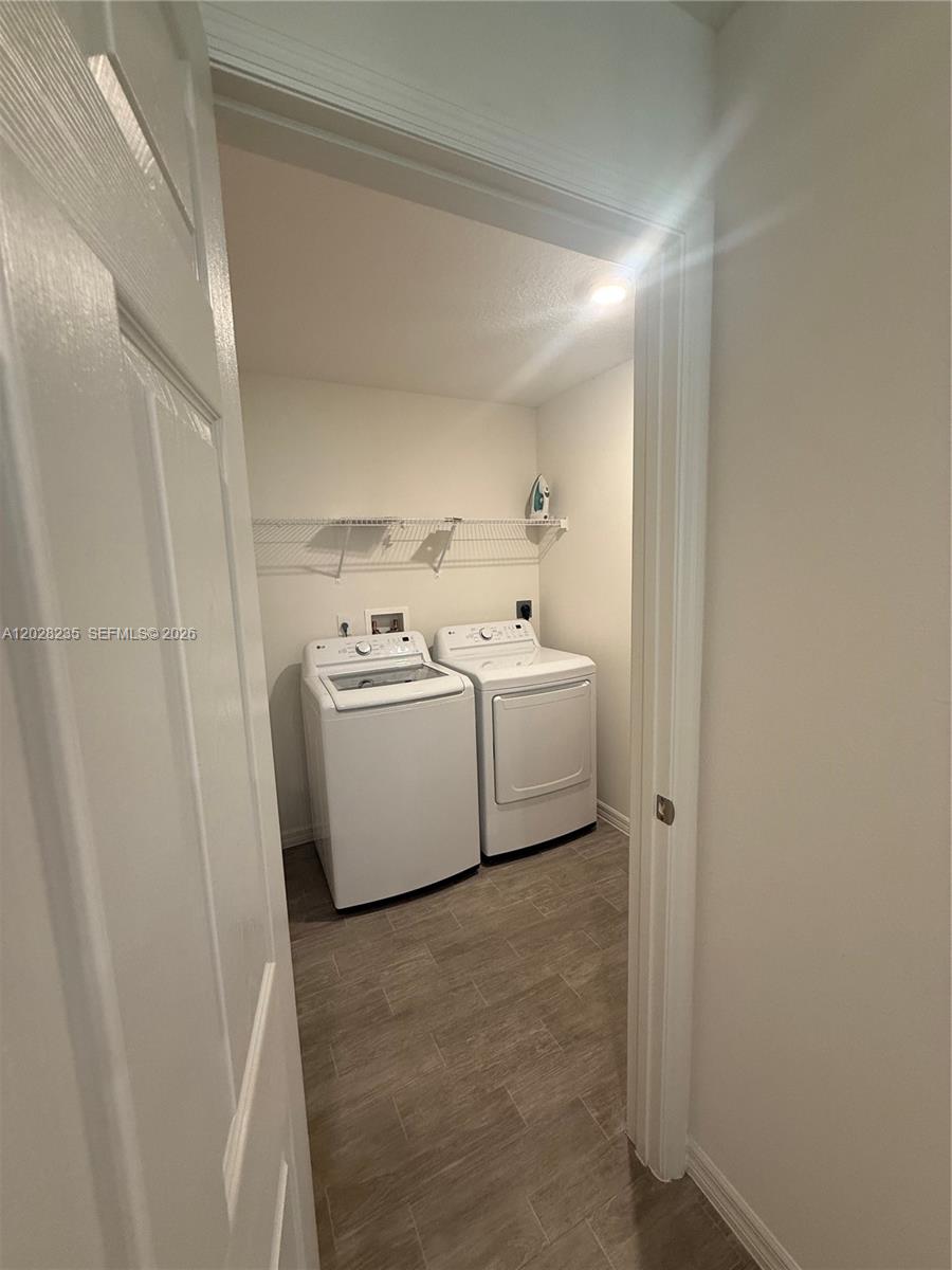 A laundry room features a white washer and dryer set beneath a wire shelf — PORT ST. LUCIE, FL