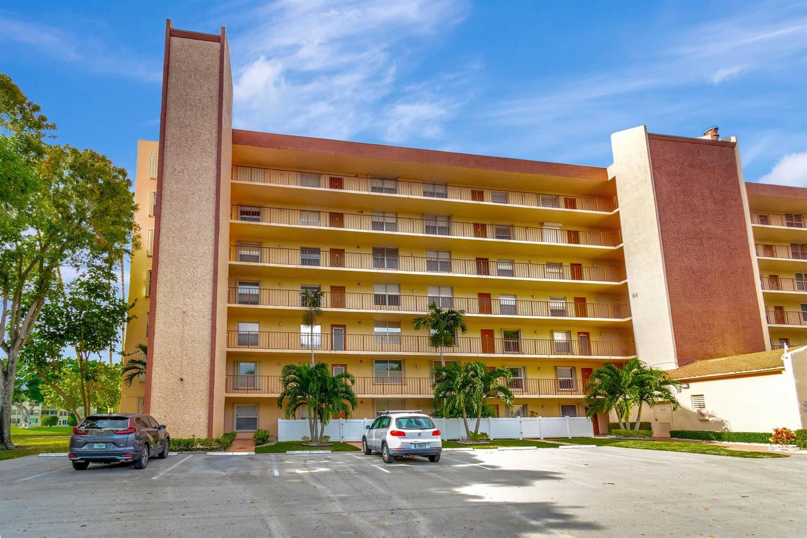 A multi-story apartment building with balconies and a parking lot in front — 14623 Bonaire Boulevard # 502, Delray Beach FL 33446, DELRAY BEACH, FL