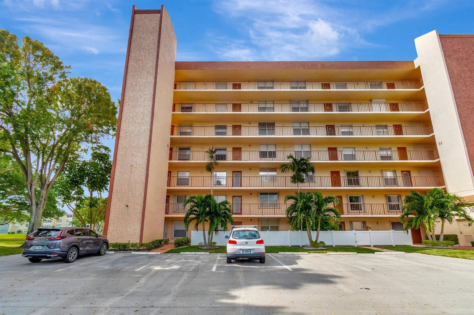 A multi-story apartment building with exterior walkways and a parking lot in the foreground — 14623 Bonaire Boulevard # 502, Delray Beach FL 33446, DELRAY BEACH, FL