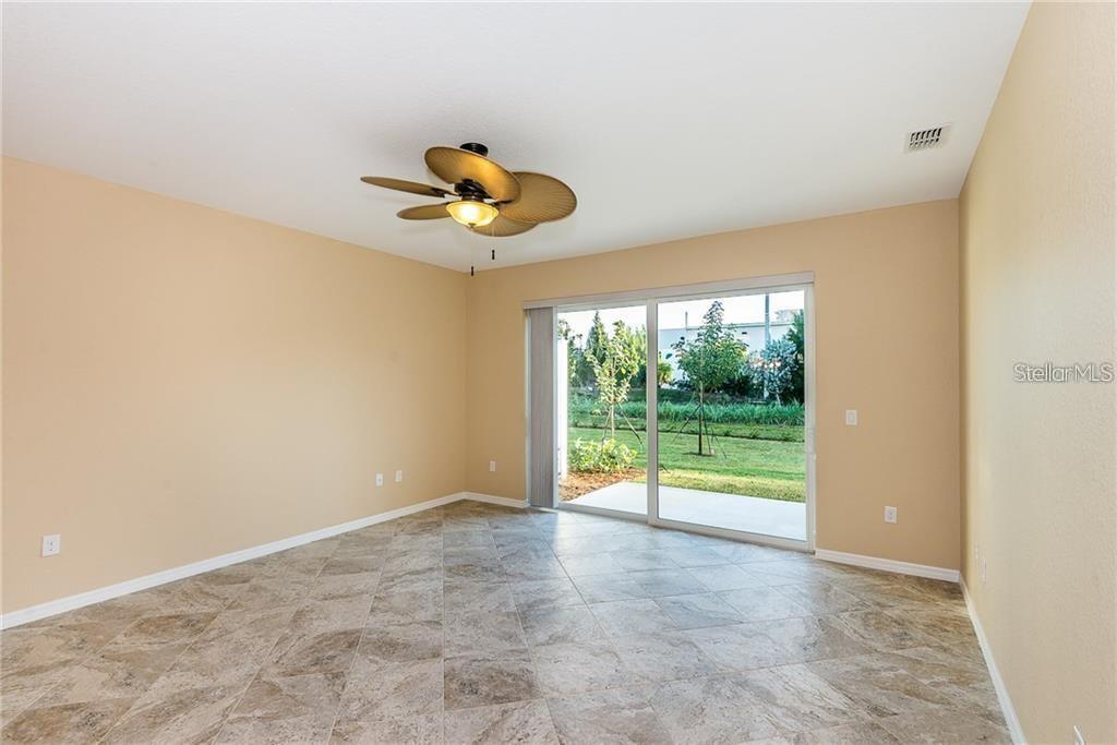 An empty room with tan walls, tile flooring, a ceiling fan, and sliding glass doors — 3948 SAN ROCCO DRIVE UNIT 112, PUNTA GORDA, FL
