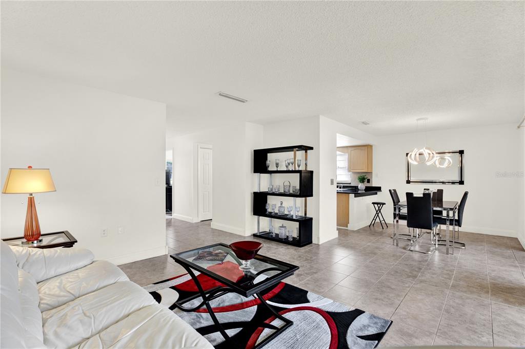 A living room and dining area with white walls, tile floors, and modern furniture — 20 SYLVIA PLACE, OLDSMAR, FL