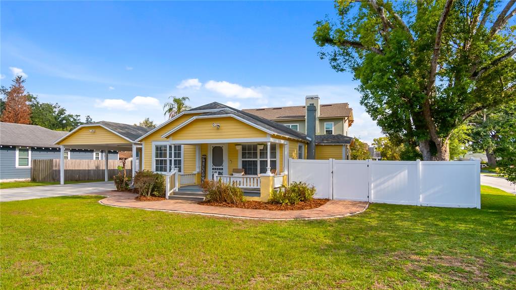 A yellow house with a front porch, carport, and white vinyl fence on a lawn — 46 W VINING STREET, WINTER GARDEN, FL