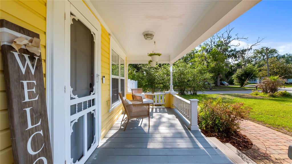 A yellow house features a covered front porch with gray wooden flooring and wicker chairs — 46 W VINING STREET, WINTER GARDEN, FL