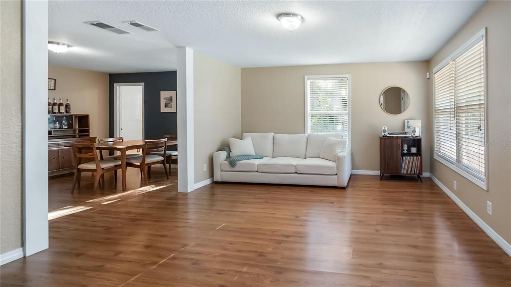 A living room with a white sofa, wood-look flooring, and an adjacent dining area — 46 W VINING STREET, WINTER GARDEN, FL