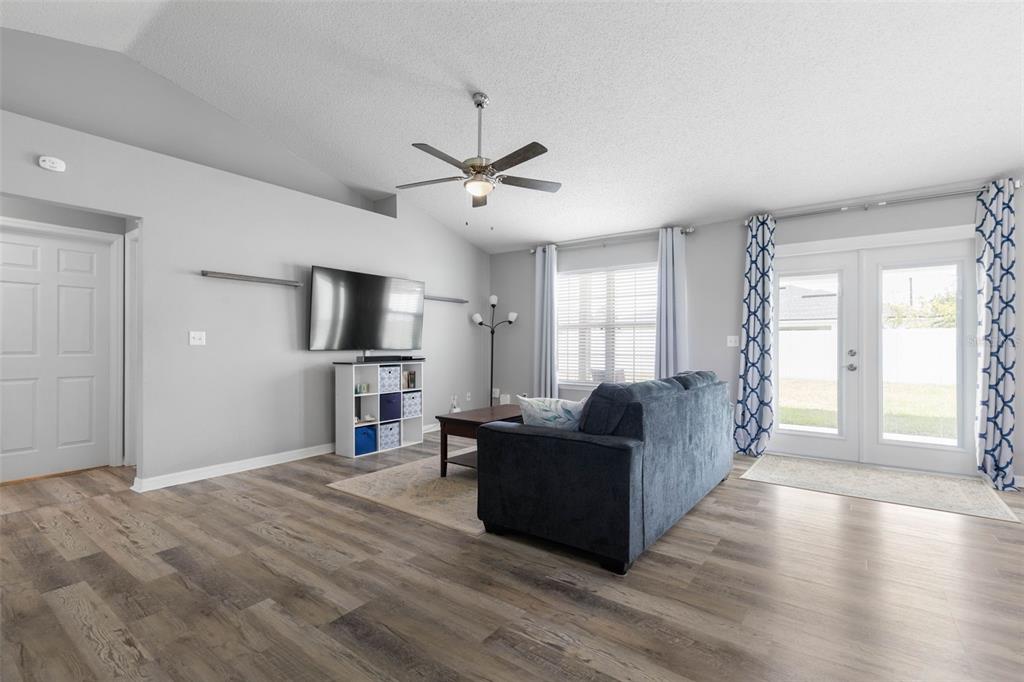 A living room features light gray walls, wood-look flooring, a ceiling fan, and a blue sofa — 34 FOREST GROVE DRIVE, PALM COAST, FL