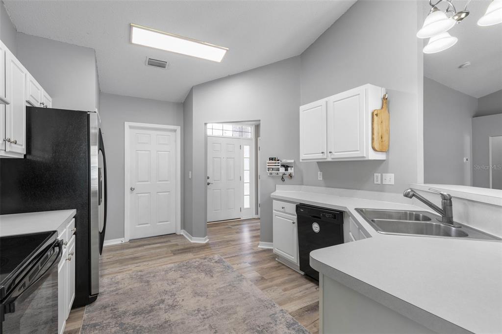 A kitchen with white cabinets, black appliances, gray walls, and wood-look flooring — 34 FOREST GROVE DRIVE, PALM COAST, FL