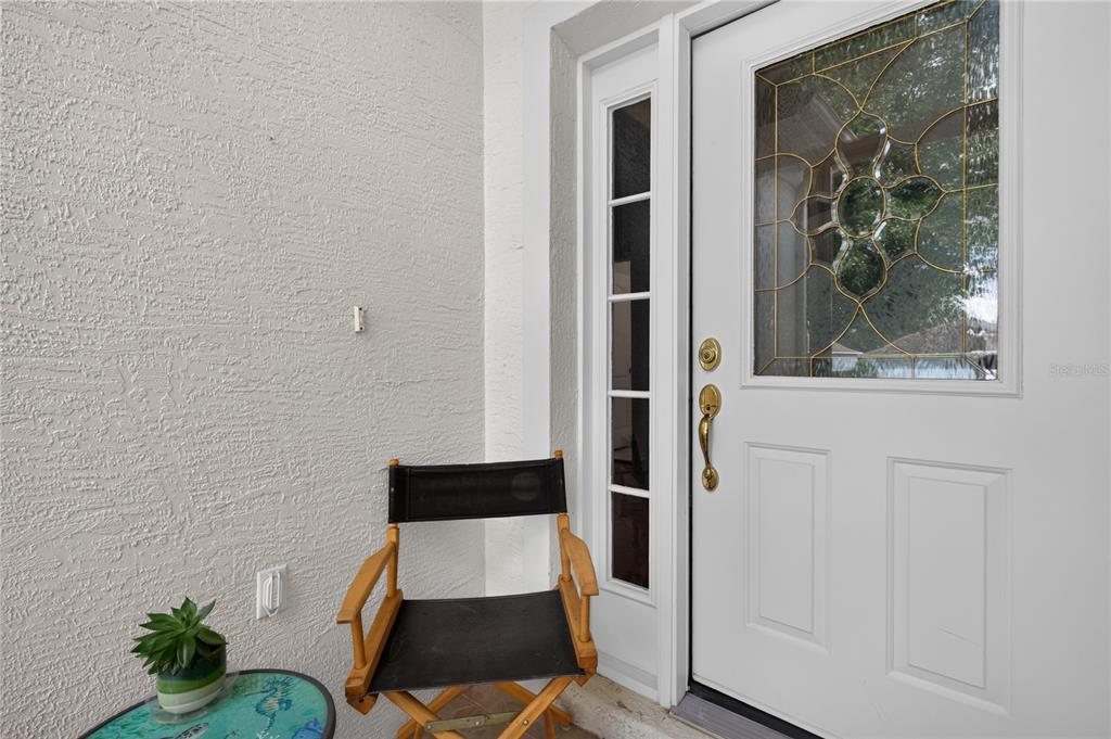 A white front door with a decorative glass insert sits beside a black director's chair — 4075 KINGSLEY STREET, CLERMONT, FL
