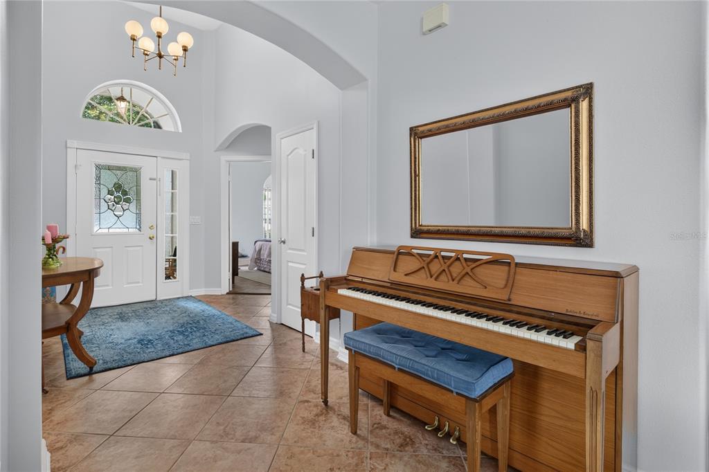 An entryway features a piano, a mirror, a blue rug, and a front door with sidelights — 4075 KINGSLEY STREET, CLERMONT, FL