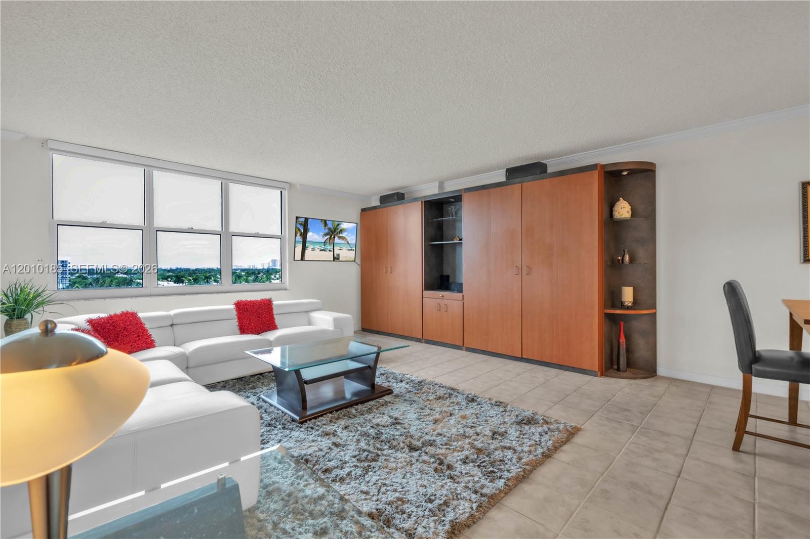 A living room features a white sectional sofa, a large wooden wall unit, and tile flooring — 2501 S Ocean Dr, Hollywood FL 33019, HOLLYWOOD, FL