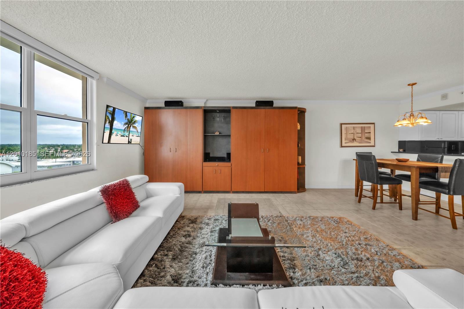 A living and dining area features a white sectional sofa, wood cabinetry, and tile flooring — 2501 S Ocean Dr, Hollywood FL 33019, HOLLYWOOD, FL