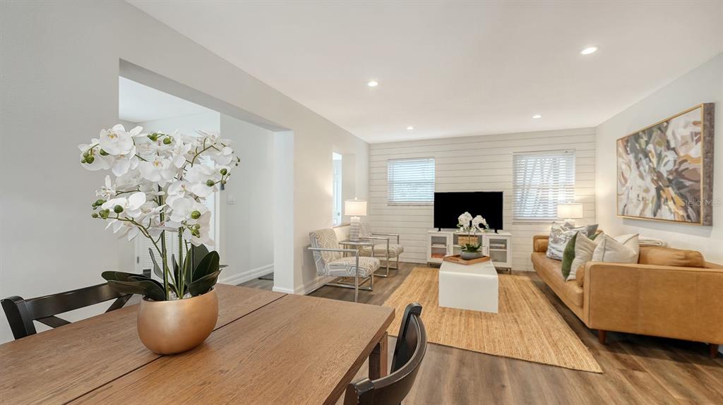 A living room with shiplap walls, a tan sofa, and a dining area in the foreground — 5610 AVENIDA DEL MARE, SARASOTA, FL
