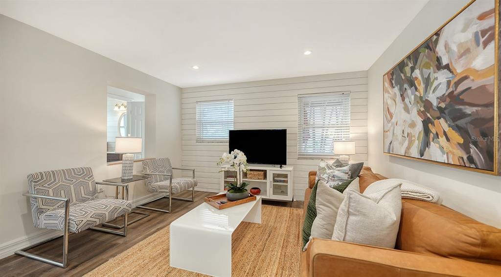 A living room features a leather sofa, two patterned chairs, and a shiplap accent wall — 5610 AVENIDA DEL MARE, SARASOTA, FL