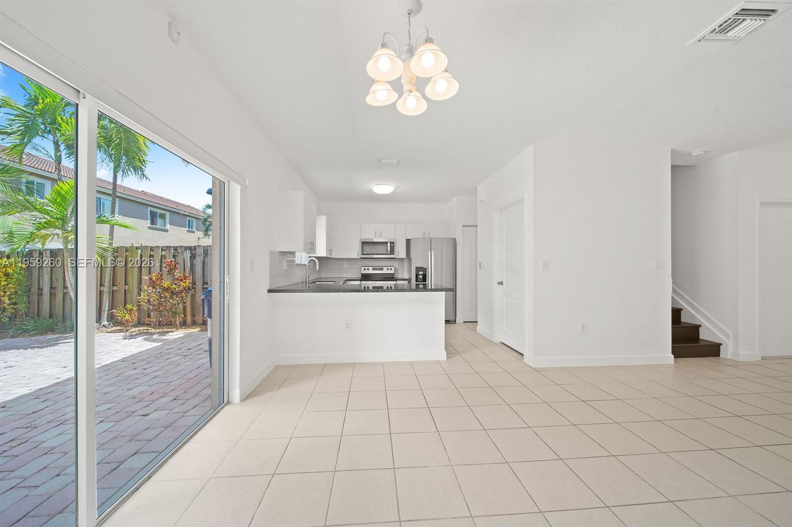 A bright kitchen with white cabinets and tile flooring opens to a patio area — 21459 SW 86th Pl, Cutler Bay FL 33189, CUTLER BAY, FL