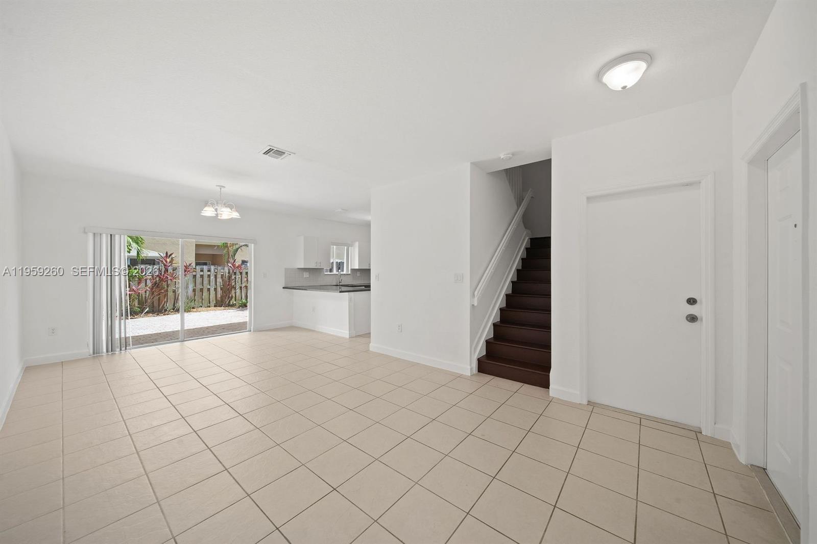 An open-concept living area features light tile flooring, a staircase, and a sliding glass door — 21459 SW 86th Pl, Cutler Bay FL 33189, CUTLER BAY, FL