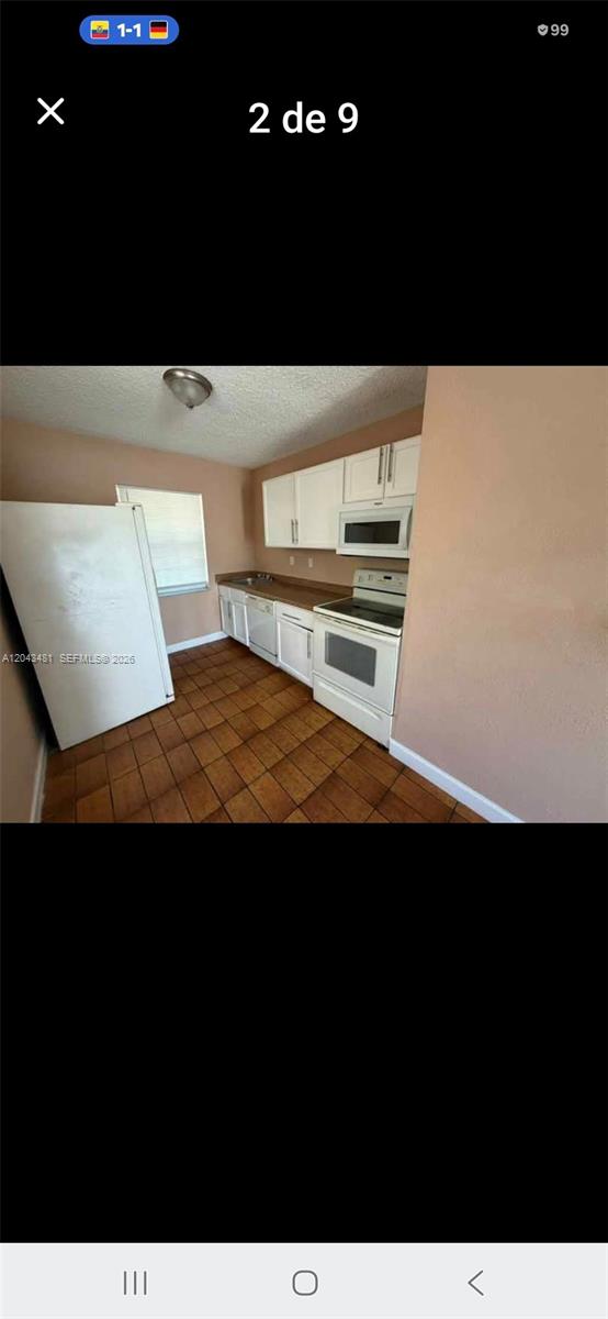 A kitchen features white cabinets, white appliances, a brown countertop, and brown tile flooring — 244 NW 14th St # 1, Pompano Beach FL 33060, POMPANO BEACH, FL
