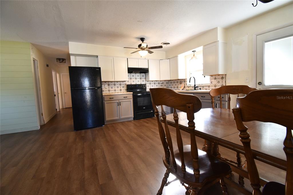 A kitchen with white cabinets, black appliances, patterned backsplash, and a wooden dining table — 2810 NE 24TH AVENUE, OCALA, FL